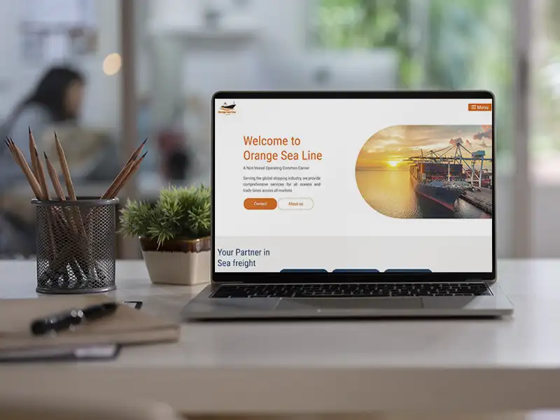 Ein Laptop auf einem Schreibtisch, auf dem eine Moderne Webseite in weiß orange angezeigt wird